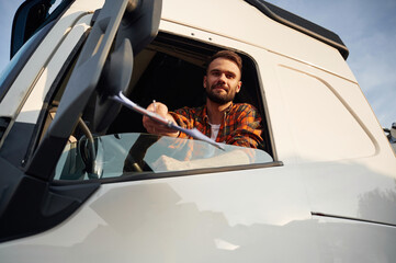 Naklejka premium Looking through the door window, sitting inside. Young truck driver in casual clothes
