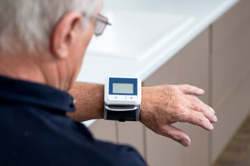 Confused and shocked aged man measuring blood pressure with tonometer himself. Health care and aging concept