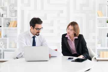 Fototapeta premium Two concentrated business people working at the desk on laptop in the office 