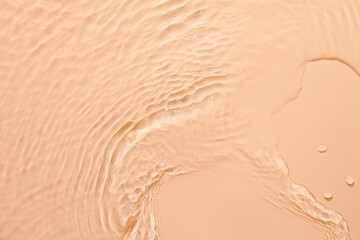 Water beige surface abstract background. Waves and ripples texture of cosmetic aqua moisturizer with bubbles.