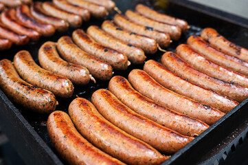 Roasted bratwurst, grilled sausages on grill on dark background.