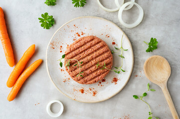 Raw plant-based meat burger in plate with vegetables.