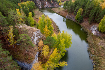 Fototapeta na wymiar rocky river banks in autumn, yellow trees and bushes