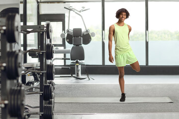 African american young man in sportswear stretching leg at the gym
