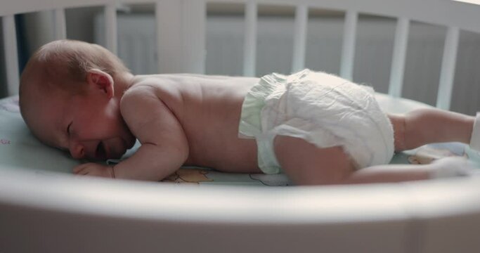 A little boy learns to crawl on the crib