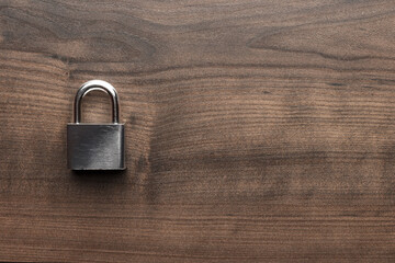 Padlock on the brown table with copy space. Flat lay image of lock on wooden background.
