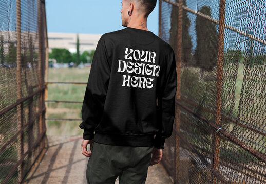 Mockup of man wearing sweatshirt with customizable color in urban setting, rear view