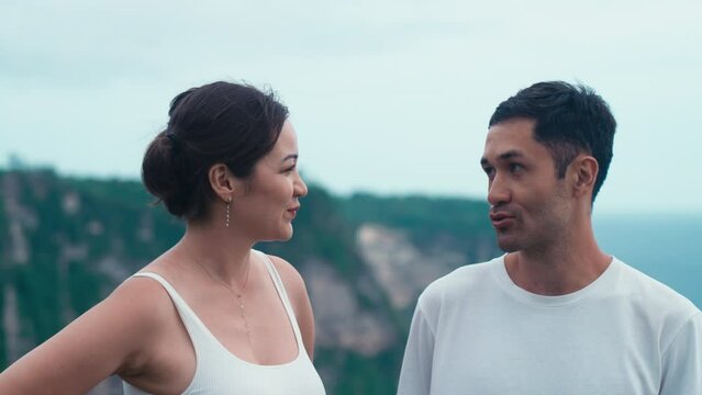 Asian man and woman they look at each other and laugh and talk. Enthusiastic emotional happy Korean couple. Travel moments for happy family on a wild seaside on summer holiday. Vacation on island