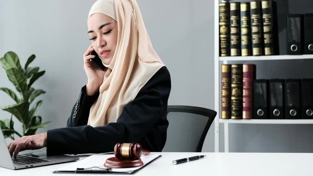 Muslim female lawyer consulting with client on mobile phone in office