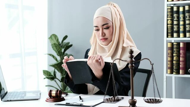 Muslim lawyer businesswoman working or reading law book in office workplace for consultant lawyer concept.
