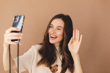 Happy young woman blogger influencer holding modern smart phone wave hand hello. Smiling vlogger...