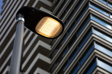 Led streetlight with a modern building in the background - obrazy, fototapety, plakaty