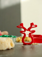 Red cookie cutter in shape of a deer with raw dough for Christmas cookies, blurred background with...