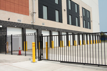 line row of exterior outdoors outside building public storage white garage units behind black metal...