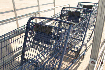 three blue shopping grocery carts outside outdoors in summer loosely inside one another under...