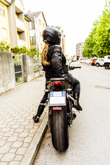 middle aged woman in motorbiker clothing riding a modern motorcycle outdoors