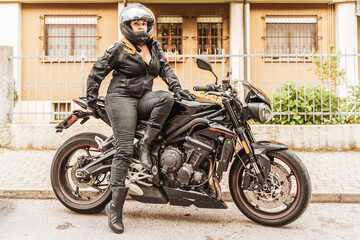 middle aged woman in motorbiker clothing riding a modern motorcycle outdoors
