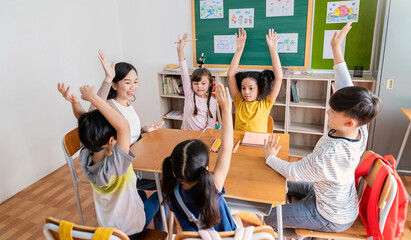 Multicultural group of students raising hand in class on lecture education, elementary school, learning people concept. Group team work of school kids with teacher sit in classroom floor raising hands