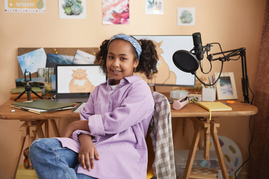 Portrait of teen black girl smiling at camera sitting by computer at home, copy space