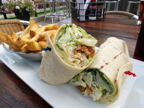 Chicken Caesar wrap, served with French fries, outside on the patio