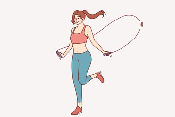 Athletic woman jumping on skipping rope for fitness, doing physical exercises, dressed in sportswear for gym. Jumping sportwoman enjoys daily workout to stay slim and have beautiful body