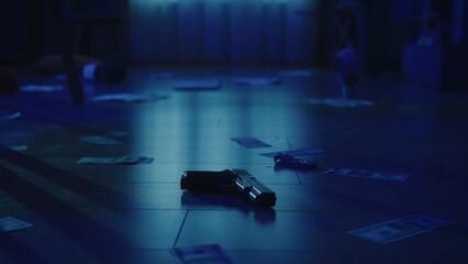 Closeup shot of the floor in the dark room with blue light. Handgun, money, jewellery and traces of...