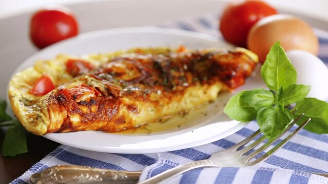 Stuffed omelette with tomatoes on a light wooden background.