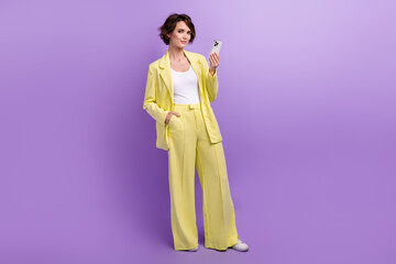 Full length photo of cheerful pretty woman dressed yellow jacket chatting twitter telegram facebook...