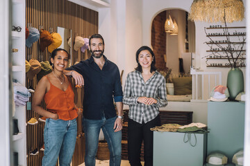 Portrait of smiling female and male sales colleagues standing together at fashion store
