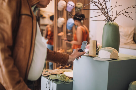 Midsection of senior man scanning QR code through smart phone at fashion clothing boutique