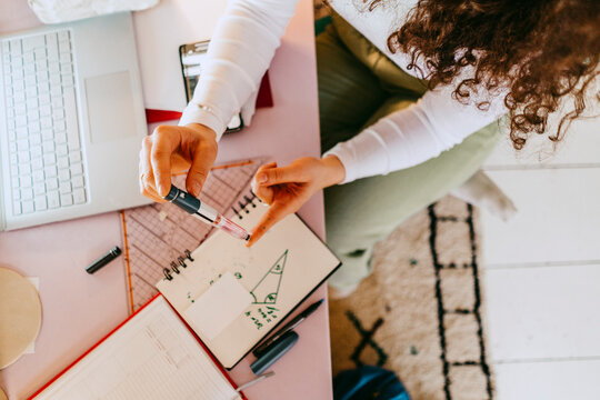 High angle view of woman using glucometer while doing homework at table