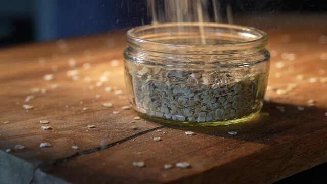 Fine oat flakes fall from above into a glass. Close--up.