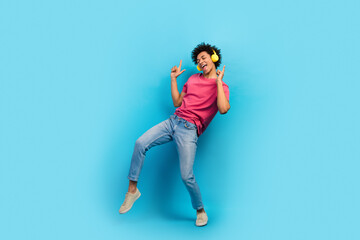 Fototapeta na wymiar Full size photo of attractive young man raise fingers up dancing earphones dressed stylish pink clothes isolated on blue color background