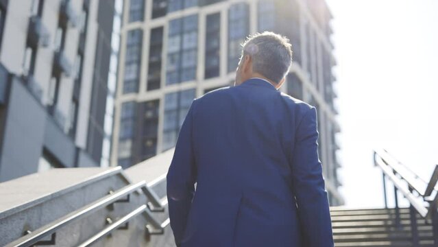 Businessman Wearing Office Formal Suit, Walking Outdoors in Urban City. Businessman Goes Up to Success - Key to Success. The Man Feels Fame and Cash Flow