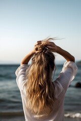 rearview shot of a woman holding her hair up by the sea with copyspace