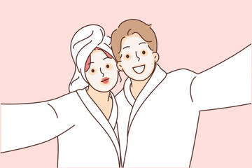 Man and woman with cosmetic masks on faces, dressed in bathrobes to perform SPA treatments