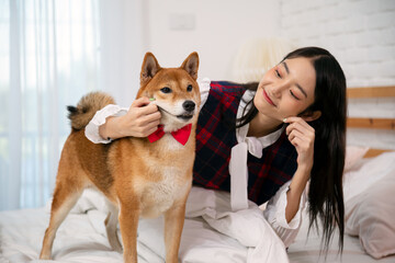 Young Asian Woman Engaging in Playtime with Her Beloved Shiba Dog in Bedroom; Playful Happiness with Pets