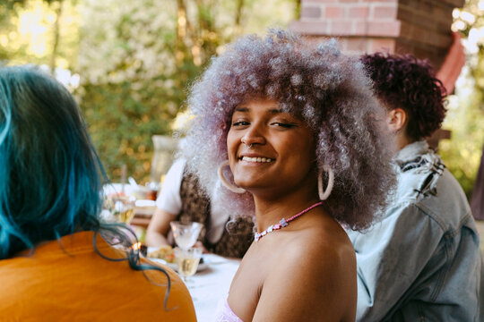 Side view portrait of smiling transwoman with curly hair during dinner party in back yard