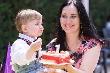 Family bond and celebration - 1 year old baby boy and his mother special day, delighting in a birthday cake candle. 