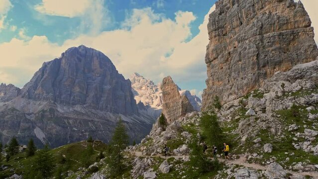 Aerial group of hikers with backpacks hiking trail path and climbing Dolomites mountain. Group of friends summer adventure journey in nature. Travel exploring Alps, Dolomites, Italy