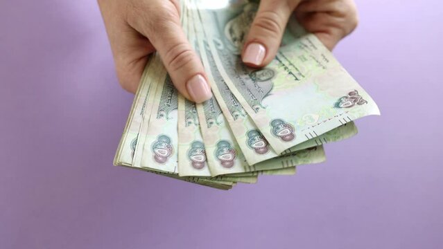 Woman counting AED dirhams in hands, closeup