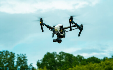 White drone over the forest. Dron against the cloudy sky. The flight of the copter in the sky