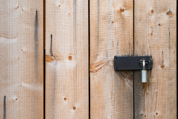 Old wooden door locked with padlock. Wooden background. Close up.