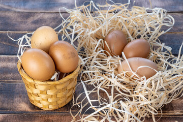 Eggs in a wicker basket. Homemade chicken eggs. Eggs on straw. Brown homemade chicken eggs