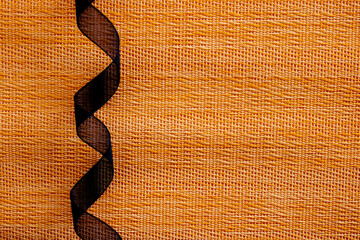 rolled black ribbon on orange textures background. halloween concept