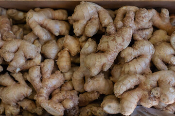 Fresh ginger root in wooden box at market store.