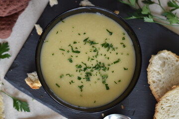 zucchini and cheese cream in a black bowl with a slate plate and bread