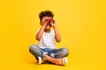 Full length photo of funky cute little boy dressed white t-shirt looking binocular empty space isolated yellow color background