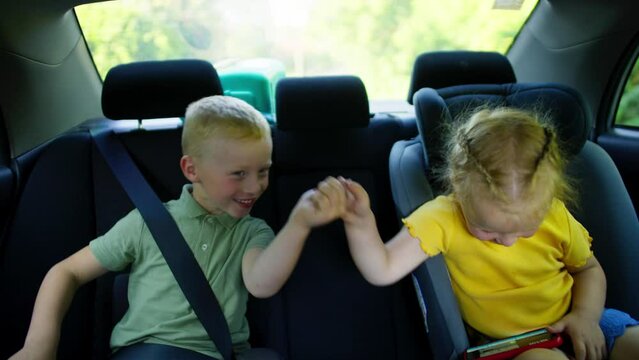 Happy children in child seats having fun while traveling in a car with their parents. Have a safe ride with your seat belts on. High quality 4k footage