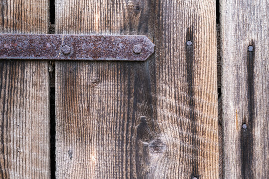 Old wooden door with rusty hinge, close-up, background.